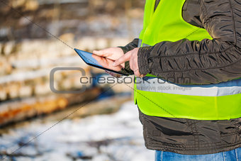 Lumberjack with tablet PC in cleared forest
