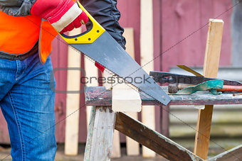 Carpenter sawing plank on to the work table