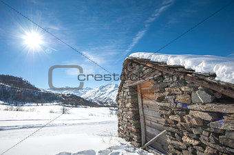 Isolated snowy mountain hut in the sun
