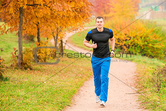 athletic man running in the park on a footpath