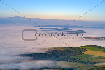 Beautiful landscape view of hills and meadows, mist and clouds