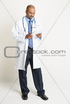 Mature Indian doctor full length using tablet pc