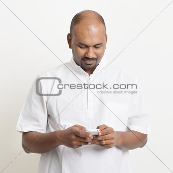 Mature casual business Indian man texting