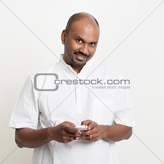 Mature casual business Indian man texting using smartphone
