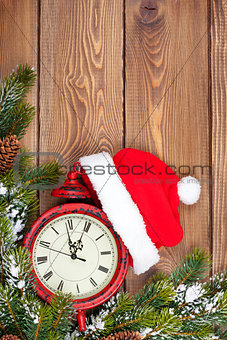 Christmas wooden background with clock, fir tree and santa hat