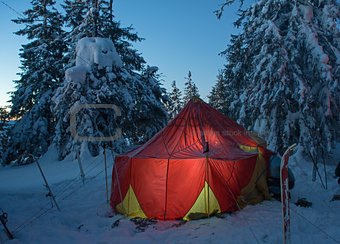 winter forest and illuminated tent
