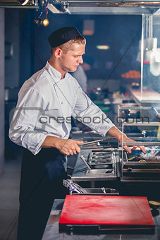 male cook preparing meal on grill