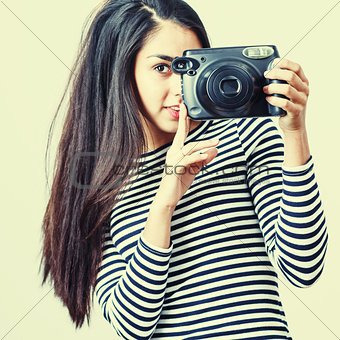Young girl wearing casual cloth posing with instant camera. 
