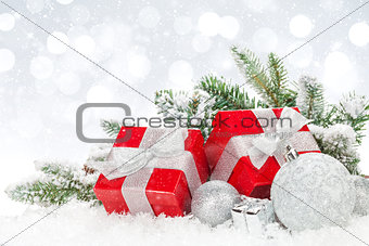 Christmas baubles and red gift boxes over snow bokeh background