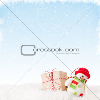 Christmas gift box and snowman in snow