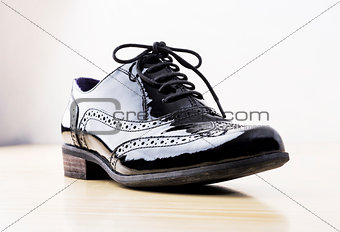 Footwear Concept. Horizontal Image. Black female classic leather shoes on the desk