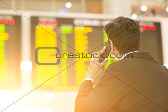 Businessman looking at airport flight timetable