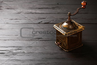 Old bronze coffee grinder on black wooden board