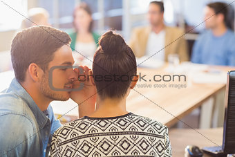Casual businessman whispering secret to his colleague