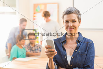 Casual businesswoman using her smartphone and smiling at camera