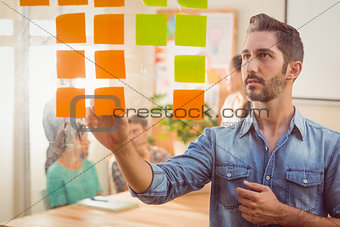 Concentrated businessman looking post its on the wall