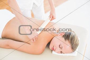Therapist waxing womans back at spa center