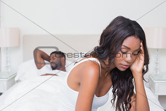 Upset woman sitting on edge of bed