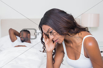 Upset woman sitting on edge of bed