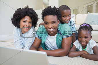 Happy family lying on the floor using laptop
