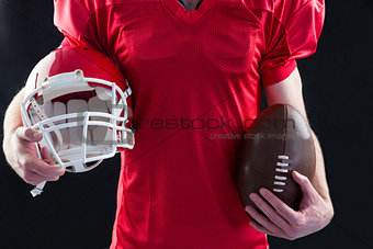 American football player holding a helmet and ball