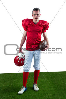 A serious american football player taking his helmet on her hand looking at camera