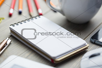 Notepad on the desk next to cup tablet and smartphone