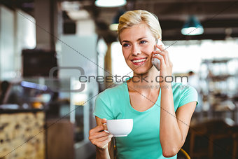 Pretty blonde woman using her smartphone with a cup of coffee