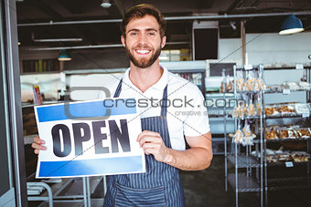 Smiling worker putting up open sign