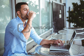 Young businessman drinking coffee beside a laptop