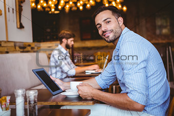 Businessman using tablet while holding cup of coffee