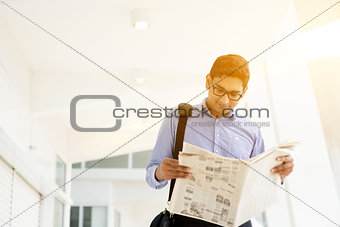 Executive reading newspaper while going to office