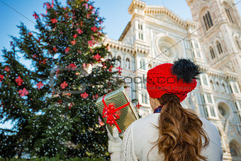 Seen from behind, woman holding Christmas gift box in Florence