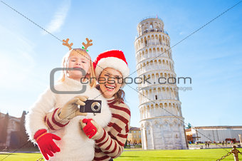 Happy mother and daughter taking photo. Christmas in Pisa
