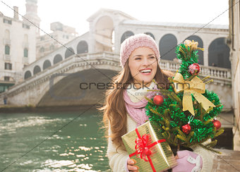 Smiling woman with Christmas tree and gift box in Venice, Italy