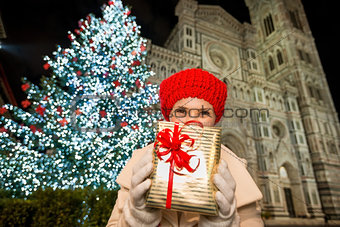 Happy woman with gift box near Christmas tree in Florence, Italy