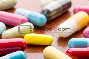 Various colorful medicine capsules on wooden background