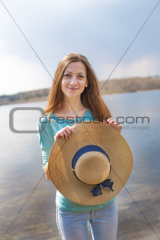 Freckled happy girl holding hat and looking at camera