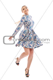 Long-haired blonde girl dancing in a beautiful blue dress.
