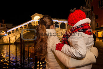 Seen from behind, mother and daughter looking on Rialto Bridge