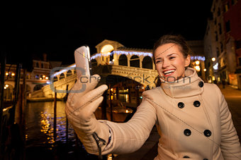 Woman taking selfie near Rialto Bridge in Christmas Venice