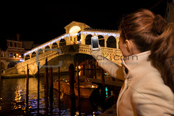 Woman taking photo of Rialto Bridge in Christmas Venice, Italy