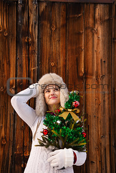 Dreamy woman with Christmas tree in front of rustic wood wall