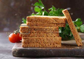 toasted rye bread with vegetables and herbs on a wooden board