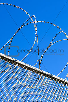 Fence with a barbed wire against the blue sky. 