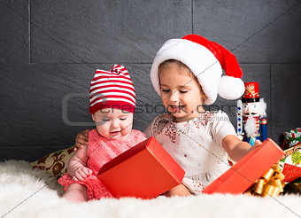 Cute kids on rug opening a Christmas present