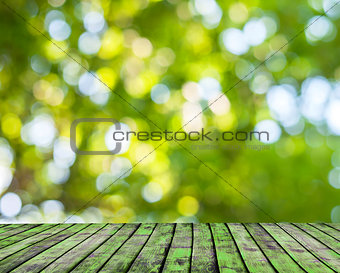 Wooden floor and green forest bokeh blur background