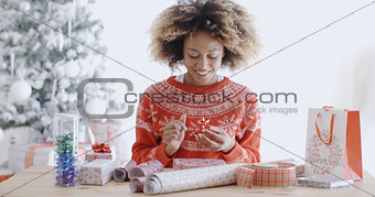 Attractive young woman wrapping Christmas gifts