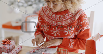 Young woman carefully wrapping a Christmas gift