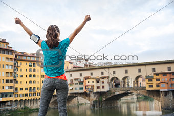 Fitness female rejoicing in front of Ponte Vecchio, Italy